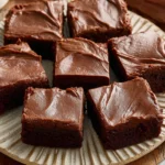 Stack of Chewy Fudgy Frosted Brownies with glossy chocolate frosting