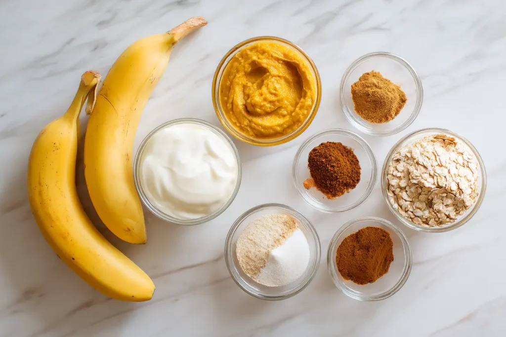 Flat lay of pumpkin pie smoothie ingredients on white marble.