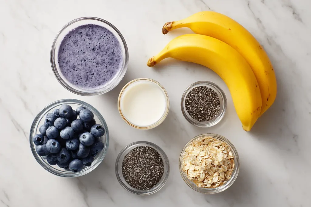 Flat lay of blueberries, banana, milk, chia seeds, and optional spinach for a smoothie.