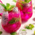 Bright pink dragonfruit mojito mocktail with mint and lime on white marble.