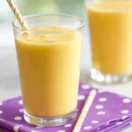 Easy 5 Minute Banana Smoothie in a tall glass with straw and citrus.
