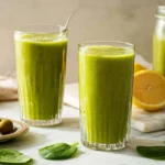 Tall glass of creamy green tea smoothie with mint and lemon.