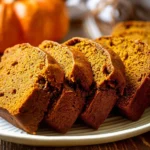 Moist pumpkin bread loaf with chocolate chips on a cooling rack
