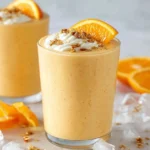 Tall frothy Orange Julius Smoothie garnished with an orange slice.