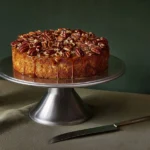 Whole pecan cake with brown sugar glaze on a wooden stand