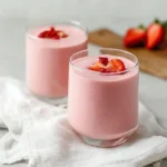 Tall glass of strawberry banana smoothie garnished with strawberry and banana.