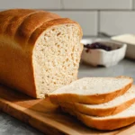 Two golden loaves of homemade whole wheat bread cooling on a rack.