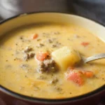 Bowl of Hamburger Potato Soup garnished with herbs and served with crusty bread