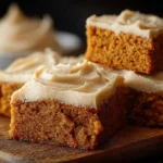 Delicious pumpkin bars with brown sugar frosting on a rustic wooden table