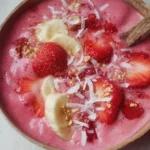 Delicious strawberry banana smoothie bowl garnished with fresh fruits and seeds