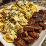 Delicious Cajun Garlic Butter Steak with Cheesy Alfredo Tortellini served on a plate.