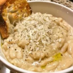Creamy white beans dish with parmesan and black pepper served in a bowl