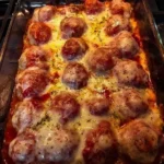 Baked meatball pasta with melted cheese and herbs on top