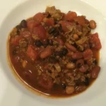 Bowl of Jamie's Award-Winning Chili garnished with fresh herbs and ingredients.