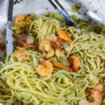 Plate of shrimp scampi with spaghetti garnished with parsley and lemon.