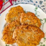 Southern fried salmon patties served on a plate with lemon wedges.